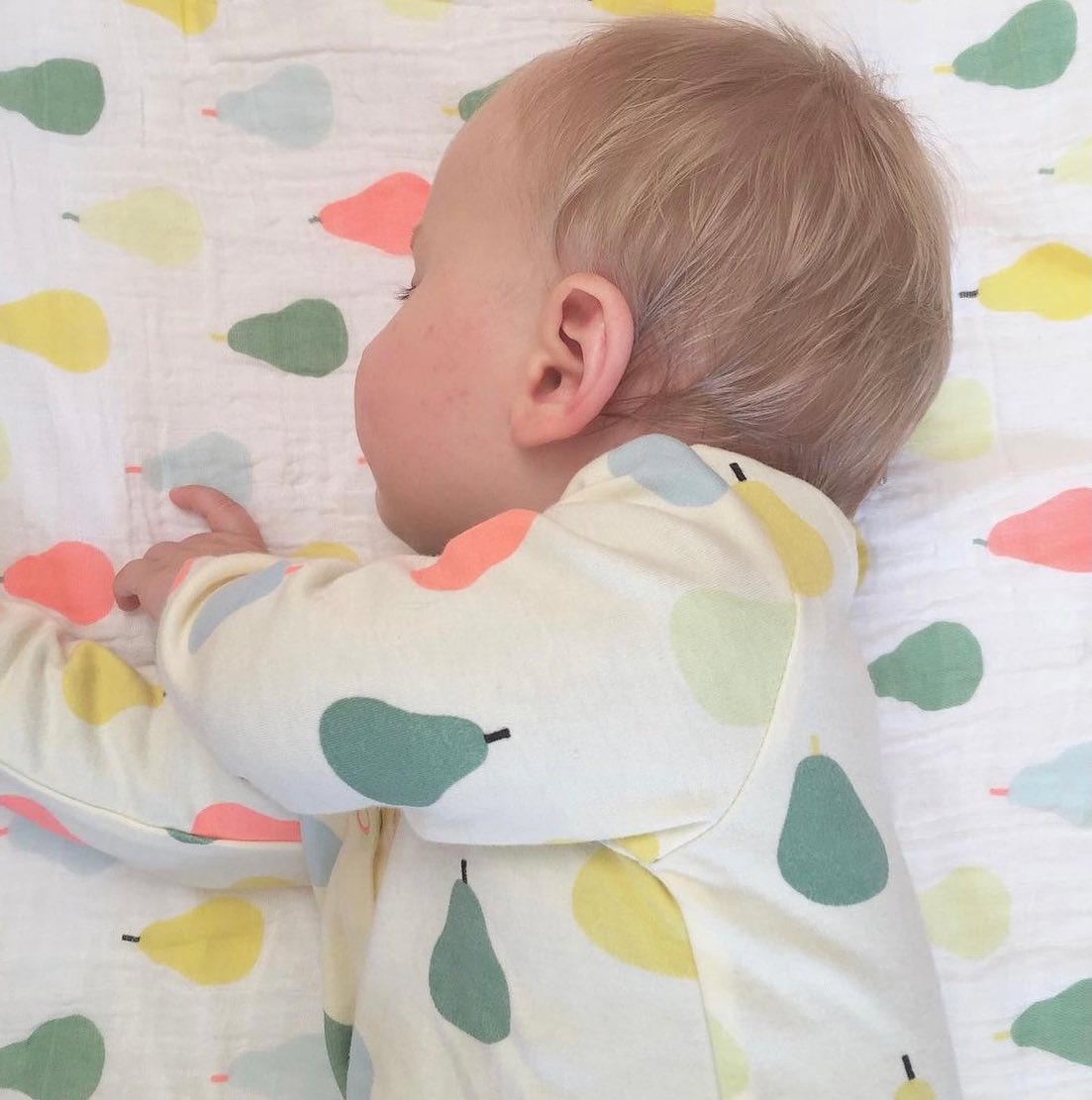 Bebé con pijama de peras de colores a juego con el textil